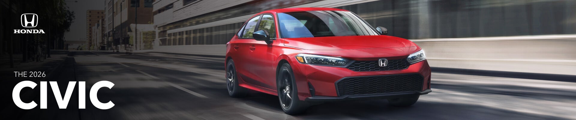 Low angle front action shot of a red 2026 Honda Civic driving down a city street.